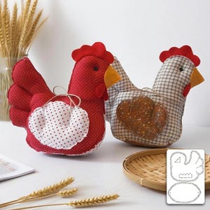 Op de afbeelding: Twee handgemaakte stoffen kippendecoraties. Eén is rood met witte stippen, de andere heeft een ruitpatroon. Beide hebben rode kammen en gele snavels. Een sjabloon voor de kippen staat in de rechter benedenhoek.