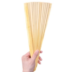 May include: A hand holds a wooden folding fan, made of thin, light brown slats. The fan is closed and the slats are arranged in a radial pattern.