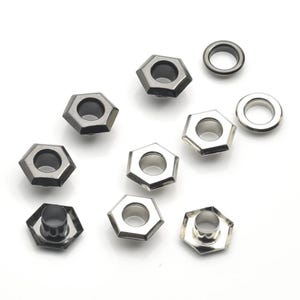 Könnte beinhalten: Eine Auswahl an Metallösen und Ösen in verschiedenen Formen. Die Ösen sind sechseckig mit dunkelgrauer Oberfläche, während die Ösen kreisförmig mit silberner Oberfläche sind. Diese Beschlagteile eignen sich ideal für Bastel- und Nähprojekte.