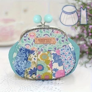 May include: A coin purse with a silver metal kiss-lock clasp and two light blue spherical beads. The exterior features a patchwork of floral fabrics in blue, green, yellow, and pink, with a tan leather label reading HANDMADE Limited edition.