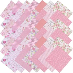 Könnte beinhalten: Eine Sammlung von rosa und weißen Stoffquadraten, die in einem Rautenmuster angeordnet sind. Die Quadrate weisen verschiedene Designs auf, darunter Blumendrucke, Tupfen, Streifen und geometrische Muster. Die Stoffe sind wahrscheinlich aus Baumwolle oder einem ähnlichen Material.