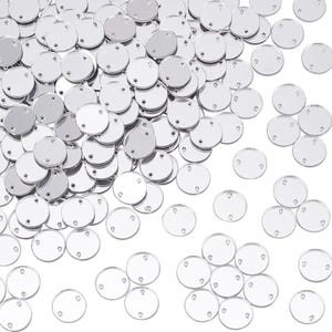 May include: A large collection of small, circular, silver-coloured mirror discs. Each individual disc features two small, aligned holes positioned near the edges, designed for attachment. The surface of each disc is highly reflective and smooth.