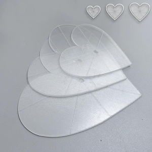 Puede incluir: Un conjunto de plantillas transparentes en forma de corazón, de varios tamaños. Las plantillas son de plástico translúcido y tienen líneas grabadas para guiar. Tres contornos de corazón más pequeños están colocados encima.