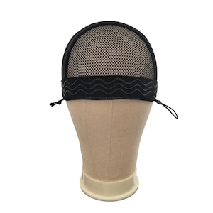 May include: A black wig grip band featuring a fine mesh top section and a wide, solid black elastic band with a wavy silicone grip pattern. The accessory includes thin, adjustable black drawstrings on both sides to secure the fit around the head.
