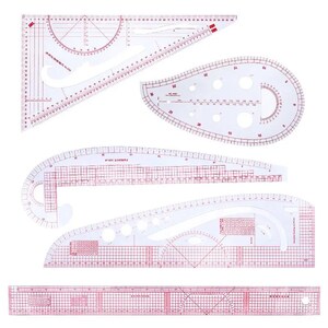 Può includere: Una collezione di righelli e modelli da cucito in plastica trasparente con segni rossi. Il set include varie forme, come triangoli, curve e bordi diritti, per la creazione di modelli e design. Misure in centimetri.