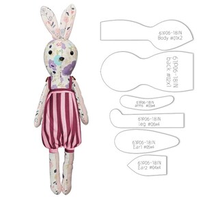 May include: A handmade bunny doll with a floral patterned head and ears, wearing a striped pink and burgundy jumpsuit. The doll has black button eyes and is accompanied by pattern pieces labeled "61P06-18IN".