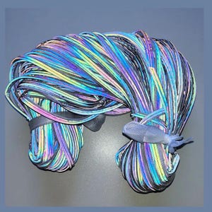 Puede incluir: Un conjunto de cordones reflectantes multicolores, con una banda gris oscura y un pequeño elemento decorativo azul. Los cordones están bien agrupados, creando una exhibición visualmente impactante de color y textura.
