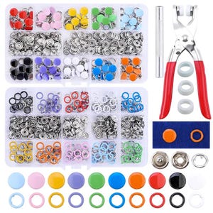 May include: A comprehensive snap fastener kit featuring two clear plastic storage containers filled with assorted colorful metal and plastic snap buttons, a metal setting tool, and a pair of pliers with red handles for installation.
