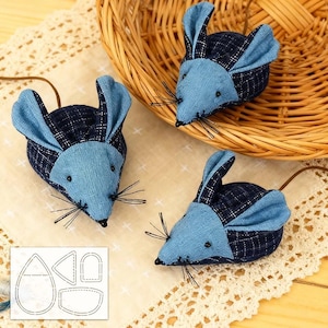 May include: Three toy mice made from blue and navy plaid fabric, with blue ears and black whiskers. Each has a brown tail. One mouse is in a wicker basket. A pattern for the mice is in the lower left corner.
