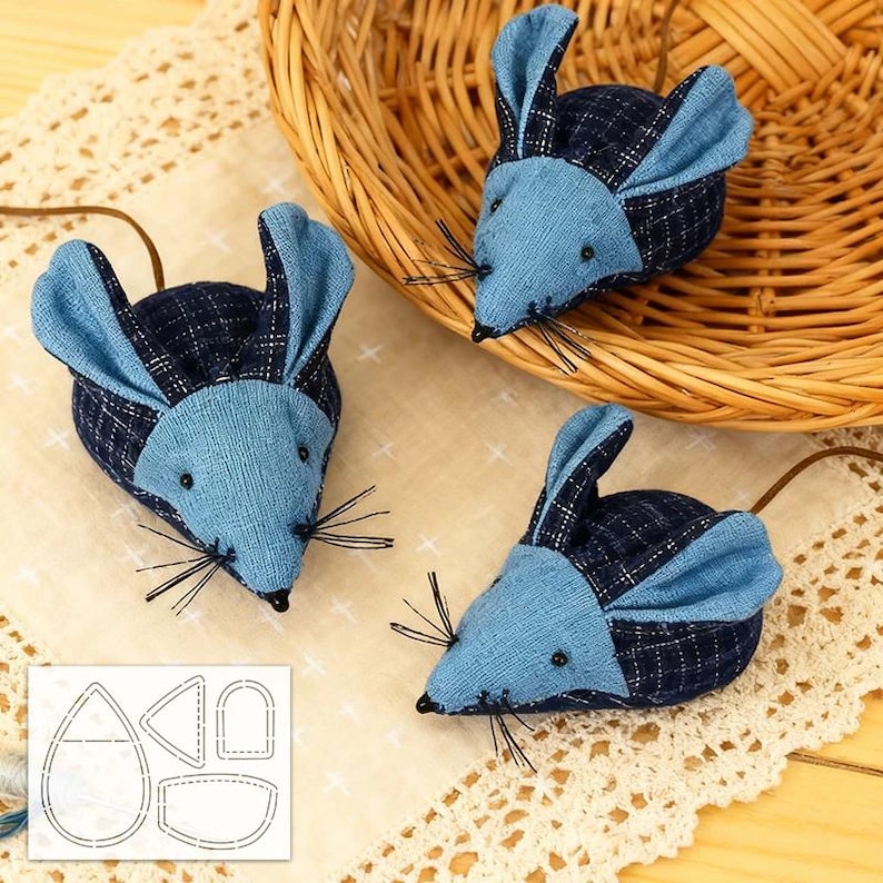 May include: Three toy mice made from blue and navy plaid fabric, with blue ears and black whiskers. Each has a brown tail. One mouse is in a wicker basket. A pattern for the mice is in the lower left corner.