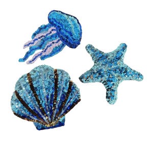 Könnte beinhalten: Drei Pailletten-Patches zum Thema Ozean: eine blaue Qualle, ein blauer Seestern und eine blaue Muschel mit braunen Akzenten. Die Patches sind mit einer Vielzahl blauer Pailletten gestaltet, die einen schimmernden Effekt erzeugen. Ideal, um Kleidung oder Accessoires einen maritimen Touch zu verleihen.