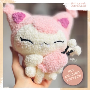 Peut inclure: Un chat en crochet rose et blanc avec un visage souriant et de petites canines. Le chat a des accents rose foncé sur les oreilles et tient un petit objet noir et blanc. Le texte "PDF CROCHET PATTERN" est dans un cercle.