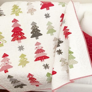 May include: White quilt with a red and white border. The quilt features a patchwork design of Christmas trees in various colors and patterns.