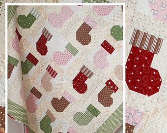 Może przedstawiać: Wzór patchworku z różnymi kolorowymi skarpetkami, sercami i innymi świątecznymi wzorami. Patchwork składa się z kwadratów i prostokątów, a kolory są jasne i radosne. Tytuł wzoru to "Stocking Stuffers", a adres strony internetowej to www.thepatternbasket.com.