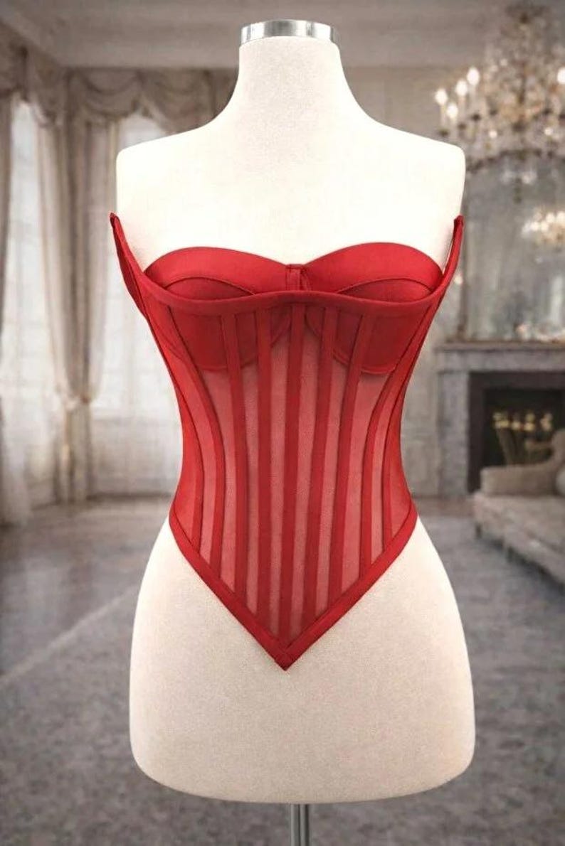 Puede incluir: Un cors&eacute; rojo exhibido en un maniqu&iacute;. El cors&eacute; presenta un corpi&ntilde;o estructurado con paneles verticales transparentes y un escote coraz&oacute;n. La prenda est&aacute; hecha de tela roja y est&aacute; dise&ntilde;ada para ce&ntilde;ir la cintura.