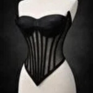 Puede incluir: Un cors&eacute; negro exhibido en un maniqu&iacute;. El cors&eacute; presenta un escote coraz&oacute;n y ballenas verticales, creando una silueta estructurada. La prenda est&aacute; hecha de una combinaci&oacute;n de materiales opacos y transparentes.