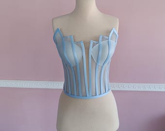 May include: A light blue corset with a mesh design and a V-shaped neckline.
