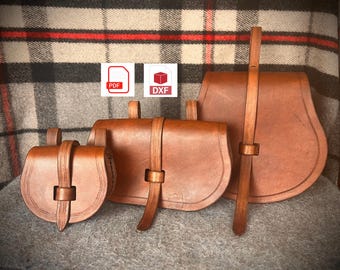 May include: Three brown leather bags with straps. The bags are different sizes and have a rustic look. The largest bag has a long strap that hangs down. The smallest bag has a decorative design on the front. The bags are on a plaid background.