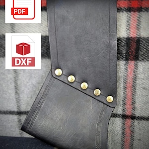 May include: Black leather holster with decorative stitching and brass rivets. The holster is designed to hold a small object, such as a knife or a tool.