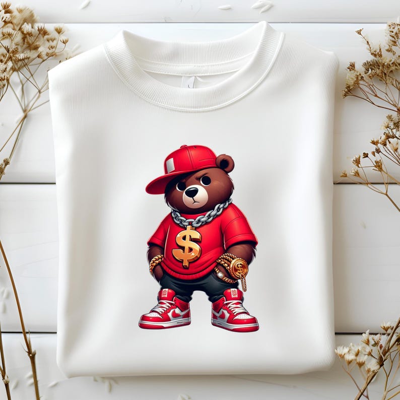 Puede incluir: Una sudadera blanca con una imagen de dibujos animados de un oso marr&oacute;n que lleva una gorra de b&eacute;isbol roja, una camiseta roja, una cadena de oro y un colgante de oro con forma de d&oacute;lar. El oso lleva zapatillas rojas.