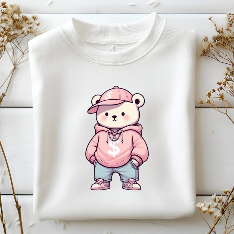 Puede incluir: Una sudadera blanca con un oso de dibujos animados rosa que lleva una sudadera rosa, una gorra de b&eacute;isbol rosa con un signo de d&oacute;lar y pantalones vaqueros azules. El oso sostiene una cadena con un signo de d&oacute;lar.