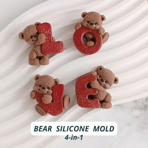 Op de afbeelding: Vier bruine beer-vormige siliconen mallen, elk met een rode letter. De letters spellen "LOVE". De mallen liggen op een wit, geribbeld oppervlak. De tekst "BEAR SILICONE MOLD 4-in-1" staat onderaan.
