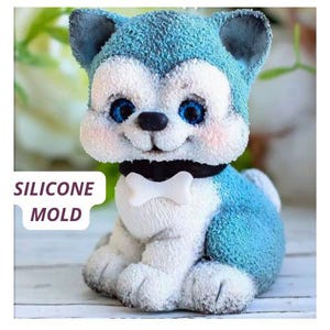 Könnte beinhalten: Eine blaue, weiße und schwarze Silikonform in Form eines Cartoon-Husky-Welpen. Der Welpe hat blaue Augen, ein schwarzes Halsband mit einer knochenförmigen Fliege und den Text "SILICONE MOLD" in einer weißen Box.
