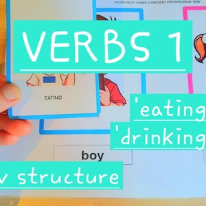 May include: Educational material with the text "VERBS 1" and "sv structure". A hand holds a card with the word "EATING" and an illustration. Other cards show "eating" and "drinking".