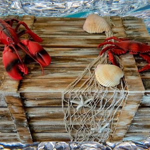 Könnte beinhalten: Eine Holzkiste mit einem roten Hummer, einem roten Krebs und Muscheln. Die Kiste ist mit einem weißen Fischernetz verziert und unter Wasser getaucht.