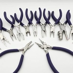 May include: An assortment of jewelry pliers with silver metal heads and dark purple handles. Various styles are displayed, including flat nose, round nose, and bent nose pliers, suitable for jewelry making and crafting.