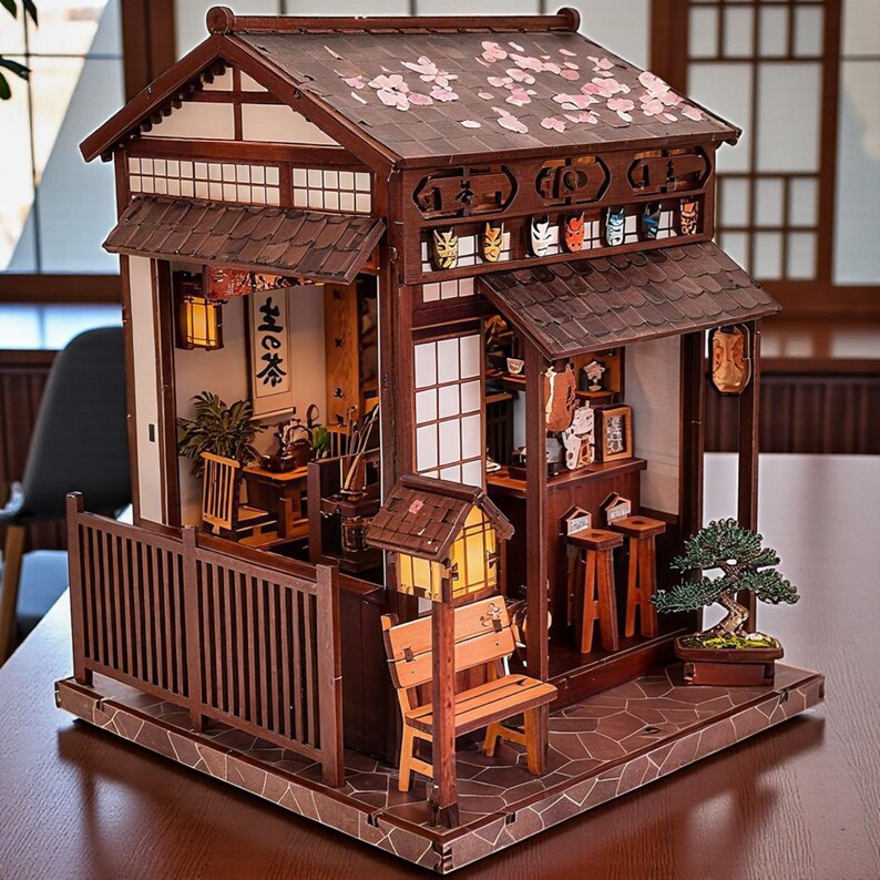 May include: A detailed wooden miniature Japanese tea house model. The model features a brown exterior with a tiled roof, paper screen windows, and a small bench. Cherry blossom accents adorn the roof. The interior includes miniature furniture and decor.