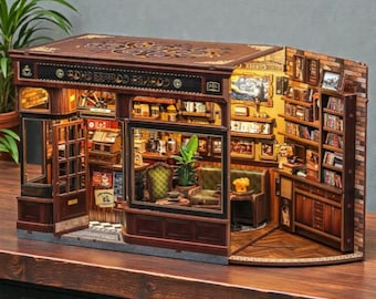 Puede incluir: Maqueta de madera en miniatura de una Corner Coffee Shop, con detalles interiores y exteriores. El modelo incluye una cafetería y una biblioteca, con muebles, libros y decoración en miniatura. El exterior es marrón con un techo decorativo.