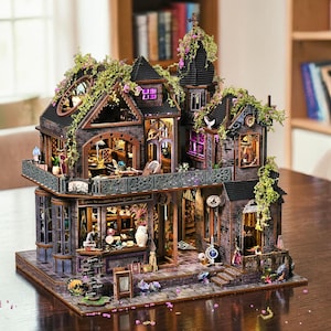 May include: A detailed, multi-story dollhouse with a gothic architectural style. The miniature house features multiple windows, balconies, and decorative elements, with a sign that reads "Explore the possibilities that your spirit craves". The exterior is adorned with greenery.