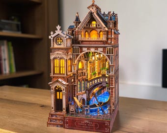 May include: A wooden 3D puzzle model of a Venetian building featuring a canal, a gondola, and illuminated windows. The structure includes architectural details like arches and balconies, with the text "VENICE NIGHT STARLIT" printed on the front base.