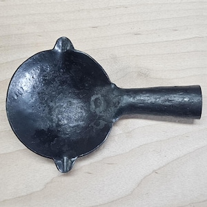 Peut inclure: Une louche en métal noir avec un bol arrondi et une longue poignée. Le bol a deux petites indentations de chaque côté.