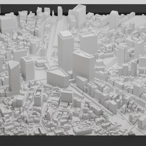 May include: A white 3D model of a city skyline with tall buildings and a street grid.