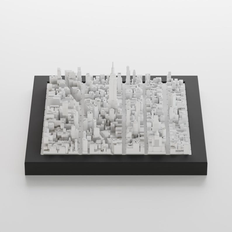 Pu&ograve; includere: Un modello 3D bianco di uno skyline cittadino, che include grattacieli ed edifici, &egrave; esposto in una cornice nera. Il modello &egrave; realizzato con piccoli cubi bianchi disposti in un reticolo.