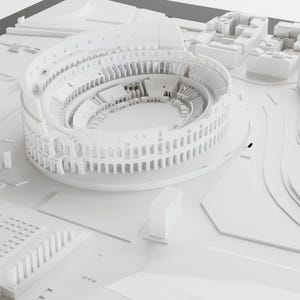 Puede incluir: Un modelo 3D blanco del Coliseo romano, un gran anfiteatro con una arena circular rodeada de gradas. El modelo est&aacute; detallado con arcos y columnas.