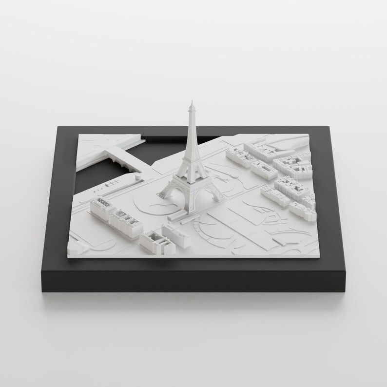 K&ouml;nnte beinhalten: Ein wei&szlig;es 3D-Modell des Eiffelturms und der umliegenden Pariser Stadtlandschaft, auf einem schwarzen Sockel pr&auml;sentiert.