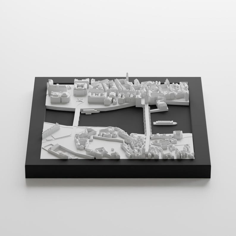 Puede incluir: Un modelo 3D blanco de una ciudad con edificios, calles y un r&iacute;o. El modelo est&aacute; colocado en un marco negro.
