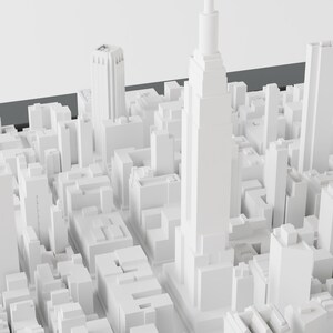 Pu&ograve; includere: Un modello 3D bianco di uno skyline di citt&agrave; con edifici alti, tra cui un grattacielo al centro.