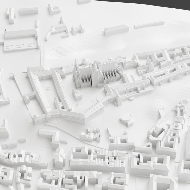 May include: A detailed, all-white architectural model of a city, showcasing various building types, including a cathedral with spires and multiple rectangular structures. The model is set against a white backdrop, emphasizing the intricate details of the urban landscape.