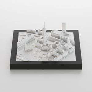 以下が含まれることがあります： 白い3Dモデルの都市のシルエットで、高い塔と周囲の建物があります。モデルは黒いベースに表示されています。