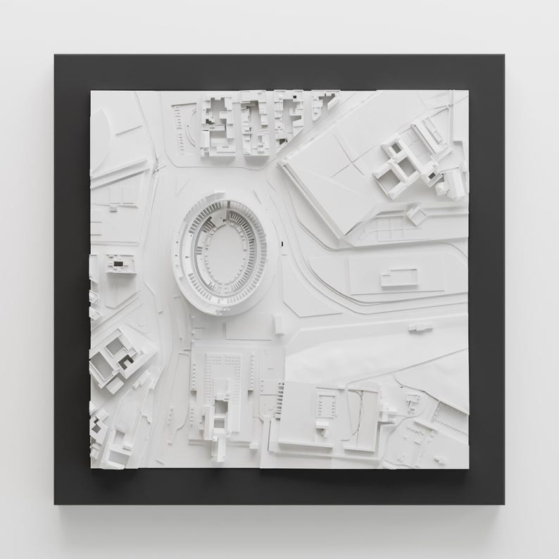 Puede incluir: Un modelo 3D blanco de una ciudad con un estadio en el centro. El modelo est&aacute; enmarcado en un marco negro.