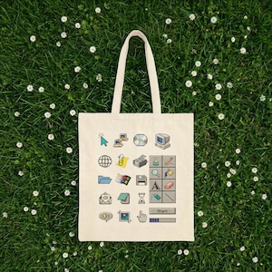May include: A cream-colored tote bag with a collection of retro computer icons printed on the front. The icons include a mouse cursor, a computer monitor, a CD, a globe, a printer, and a Windows logo. The bag has a rectangular shape and two long handles.