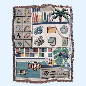 Peut inclure: Un plaid tiss&eacute; pr&eacute;sentant un design d'interface d'ordinateur des ann&eacute;es 1990. Le motif comprend des ic&ocirc;nes pix&eacute;lis&eacute;es, une palette de couleurs, un palmier, des poissons, un personnage trombone et une fen&ecirc;tre affichant le texte Login successful.
