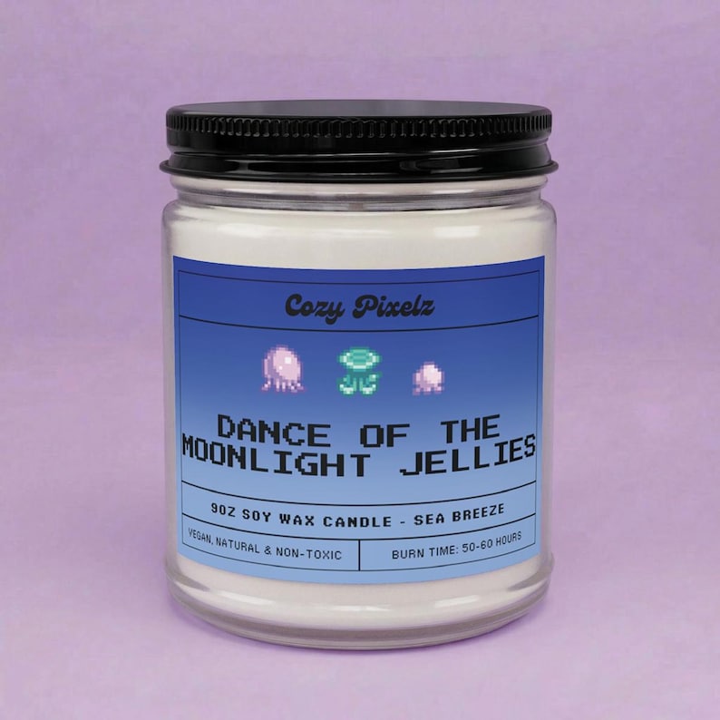 May include: A glass jar candle with a black lid and a blue label. The label reads "Cozy Pixelz" and "DANCE OF THE MOONLIGHT JELLIES". The candle is 9 oz soy wax, sea breeze scented, vegan, natural, and non-toxic, with a burn time of 50-60 hours.