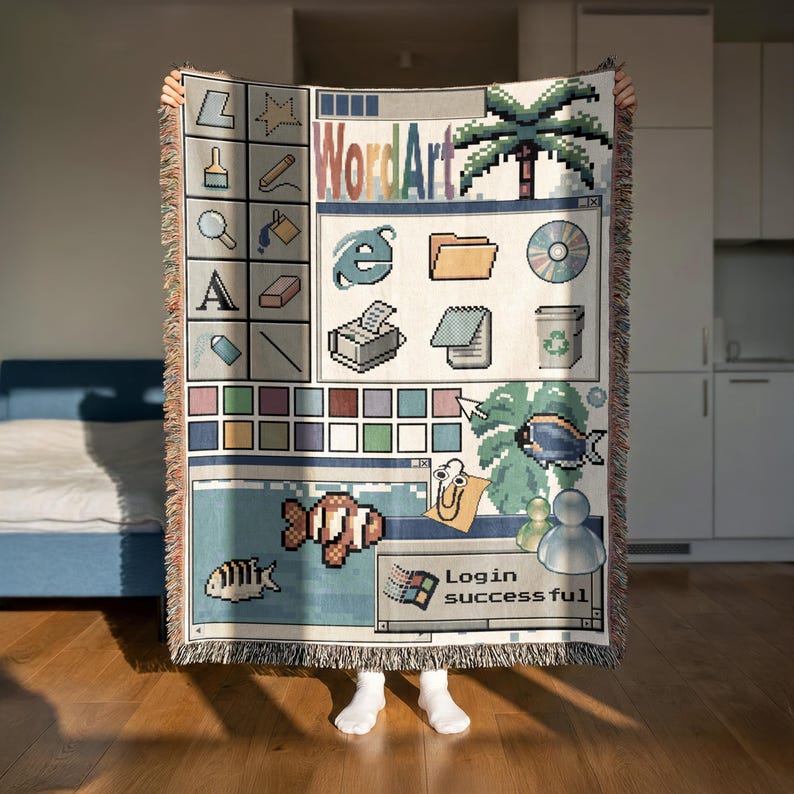 Peut inclure: Un plaid tiss&eacute; pr&eacute;sentant un design d'interface d'ordinateur nostalgique des ann&eacute;es 1990. Le motif comprend des ic&ocirc;nes pix&eacute;lis&eacute;es, un palmier, un poisson, un personnage trombone et une fen&ecirc;tre affichant le texte WordArt et Login successful.