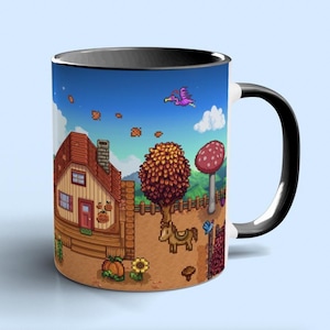May include: A ceramic mug featuring a pixelated illustration of a farm scene. The design includes a house, tree, mushroom, and a horse. The mug has a black handle and rim, with a white interior.
