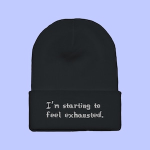 May include: Black beanie with the text "I'm starting to feel exhausted." embroidered in white.
